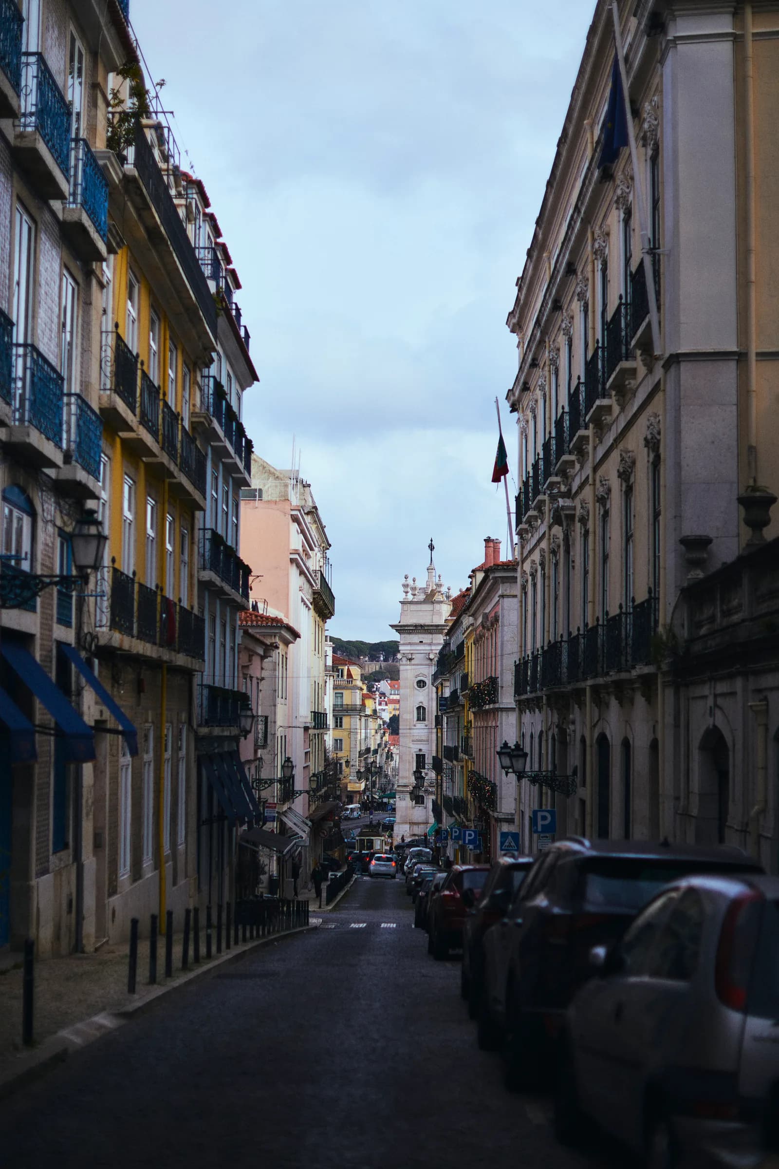 Calle de Lisboa con balcones de hierro y una torre al fondo