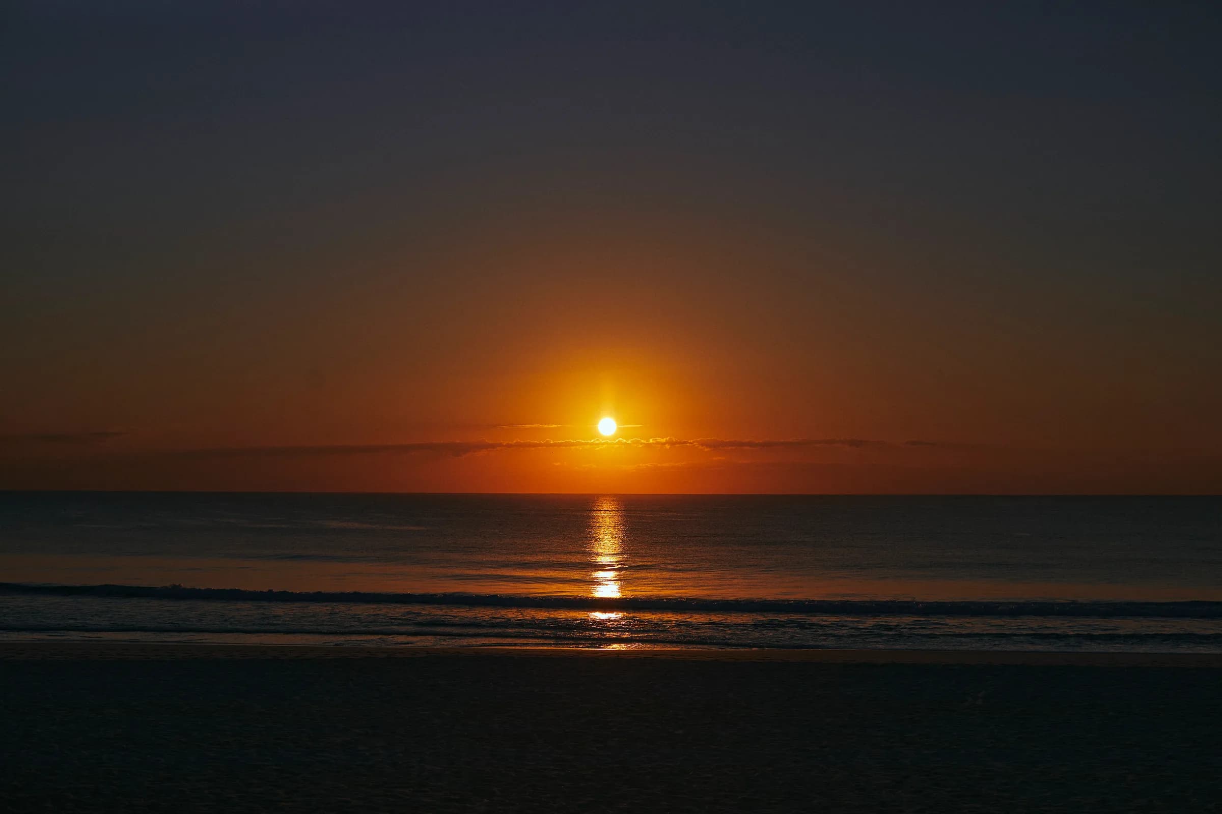 Amanecer sobre el mar con reflejo dorado en el agua