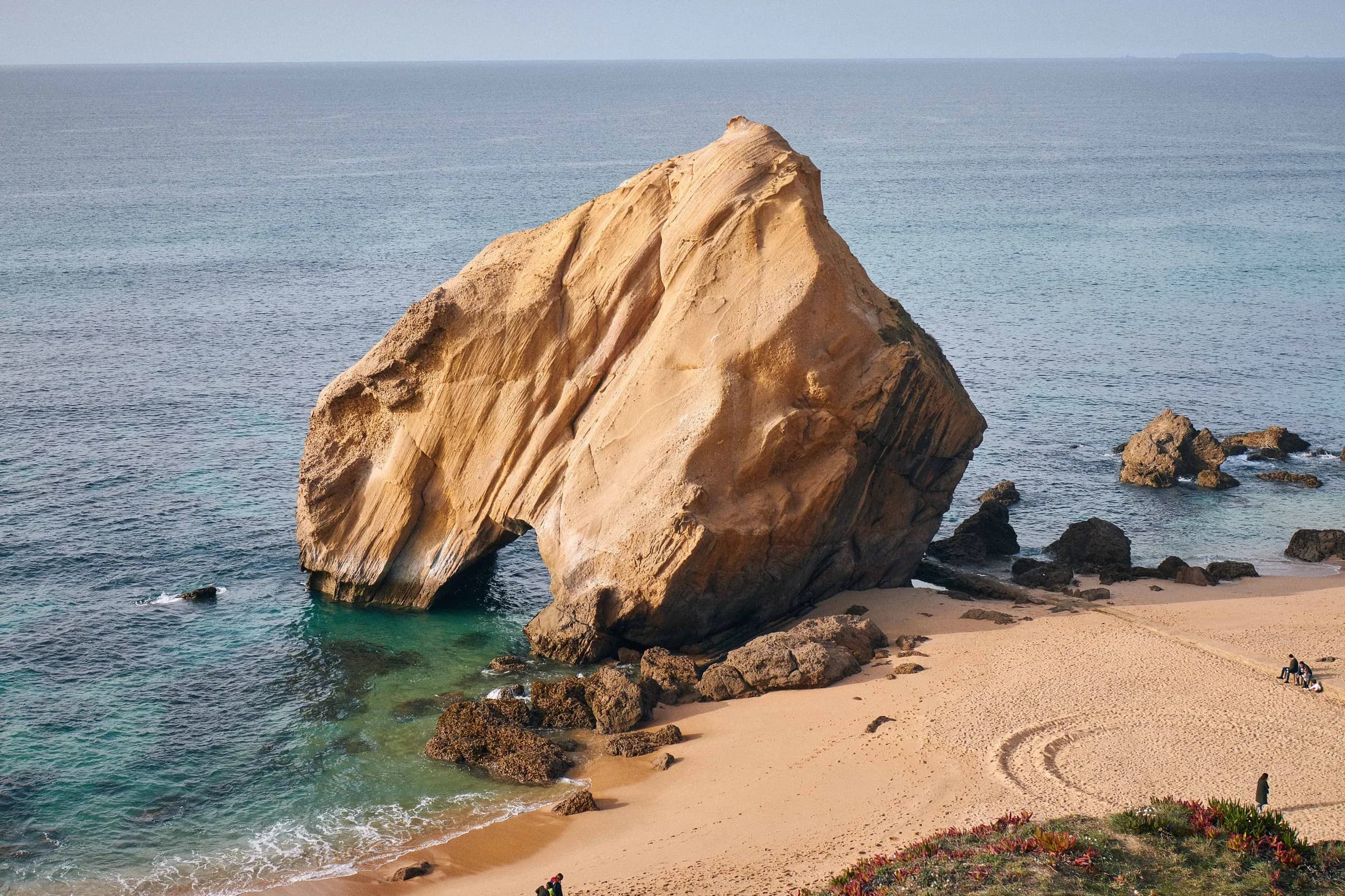 Gran roca de arenisca sobre una playa de aguas turquesa