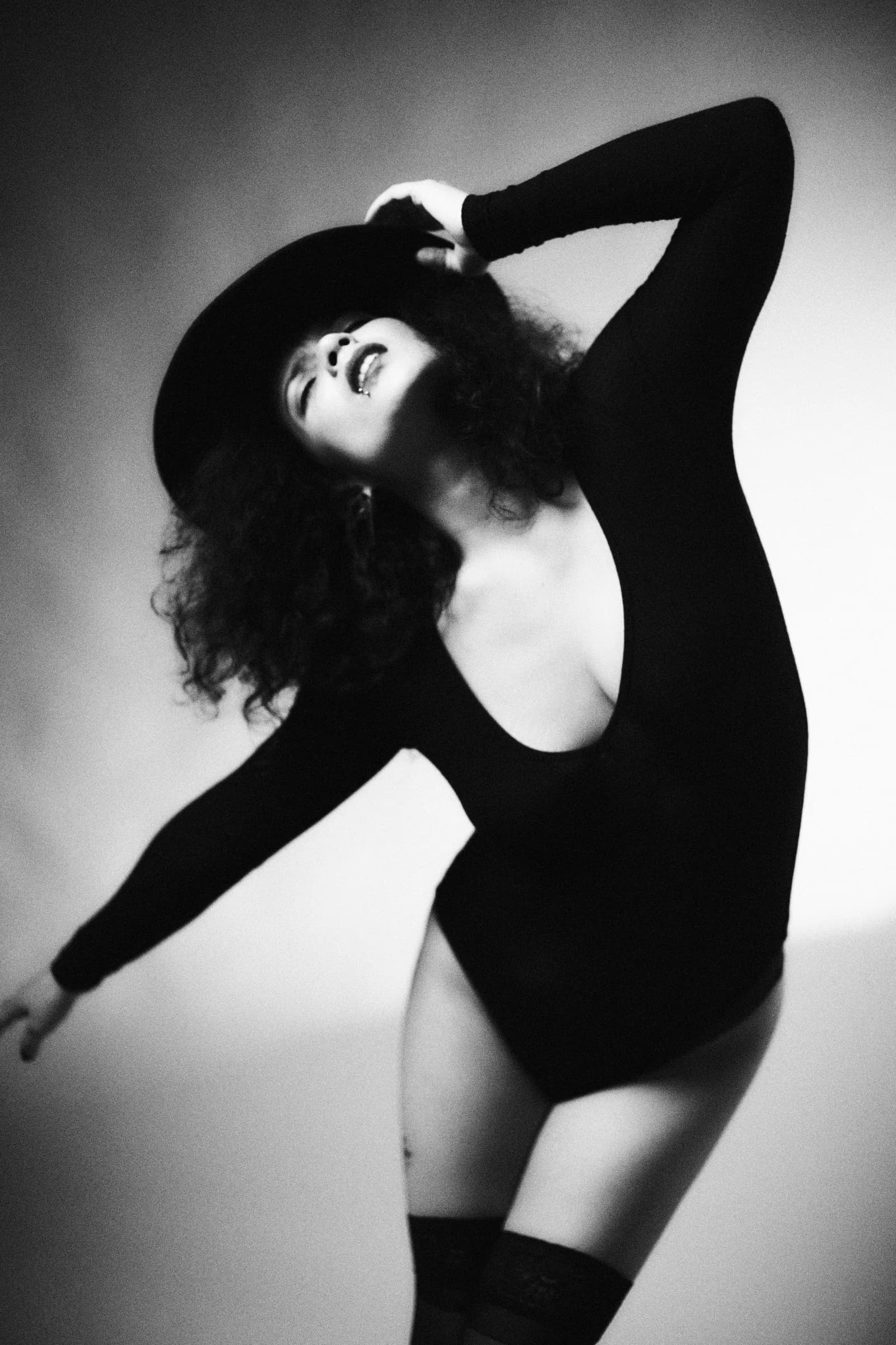 Retrato en blanco y negro de mujer con sombrero y body negro en movimiento