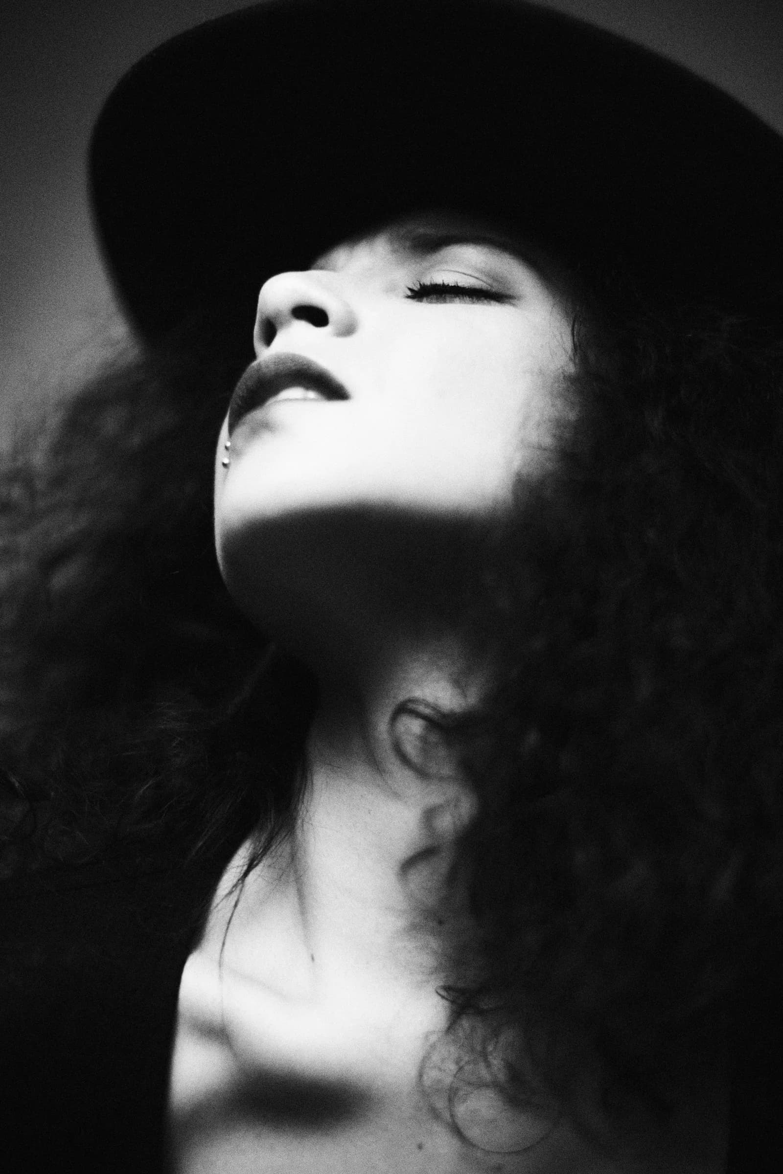 Primer plano en blanco y negro de mujer con sombrero y ojos cerrados