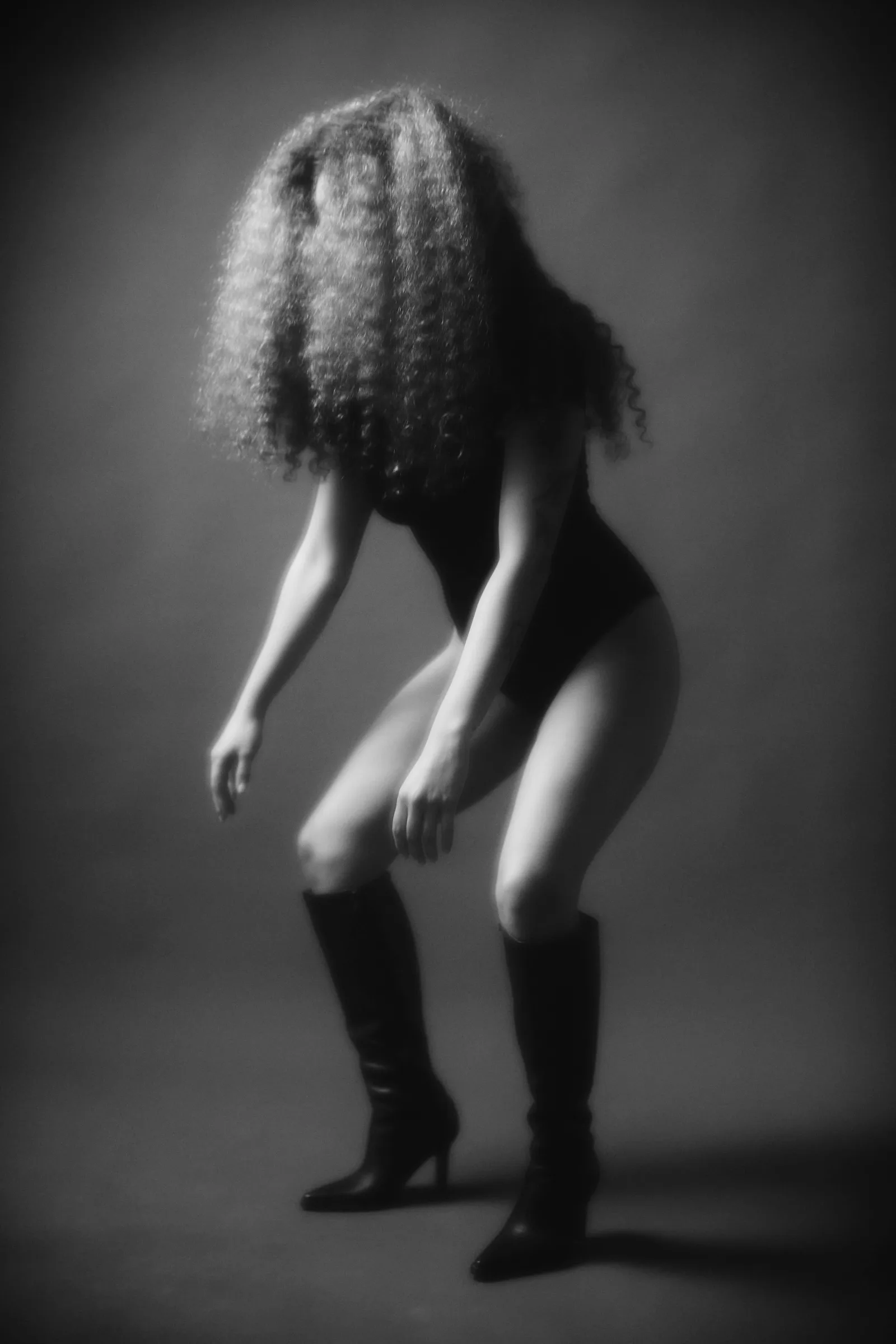 Mujer con el cabello rizado cubriéndole el rostro, en blanco y negro