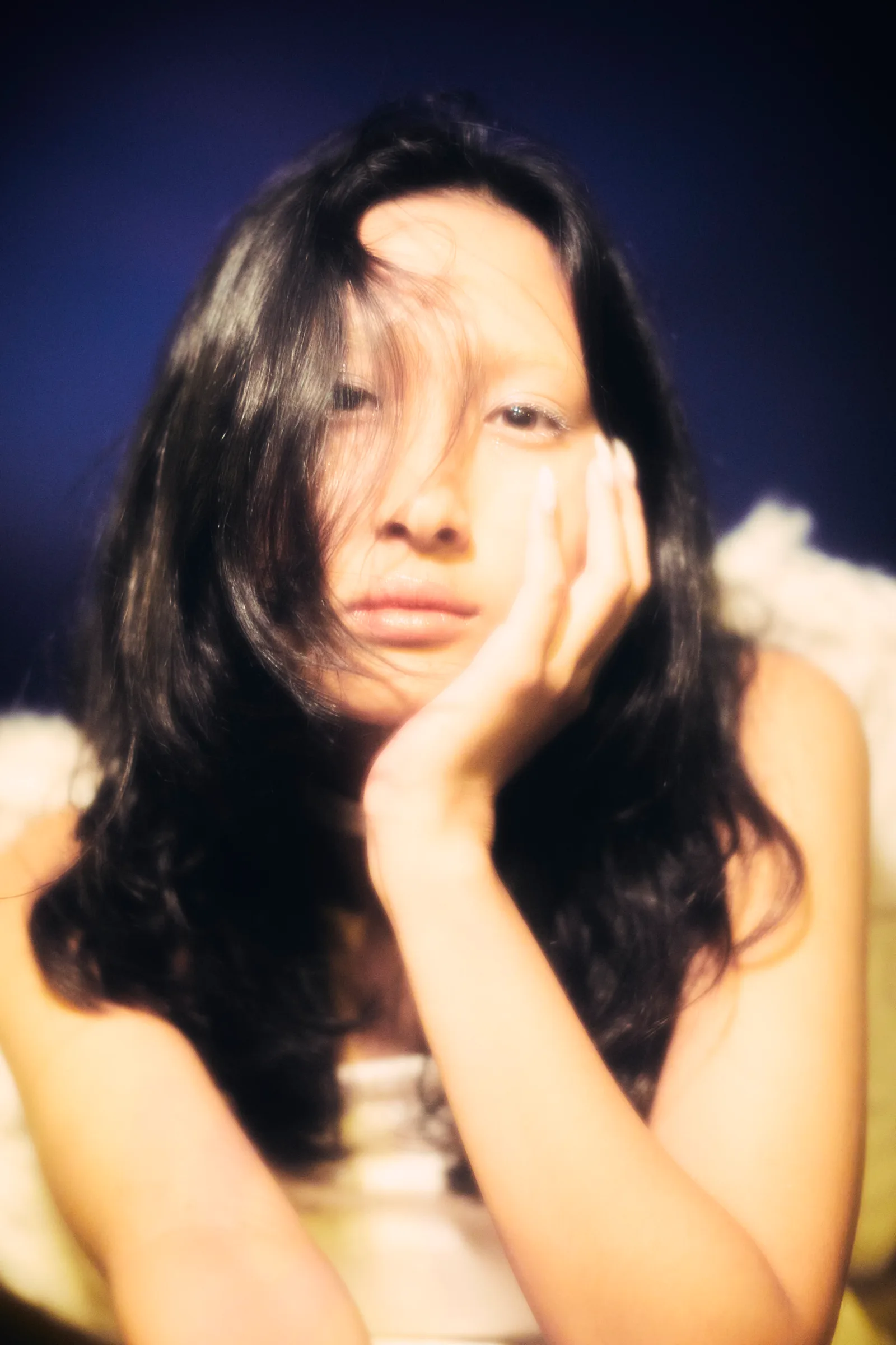 Retrato cálido de mujer con la mano en la mejilla y el cabello sobre el rostro