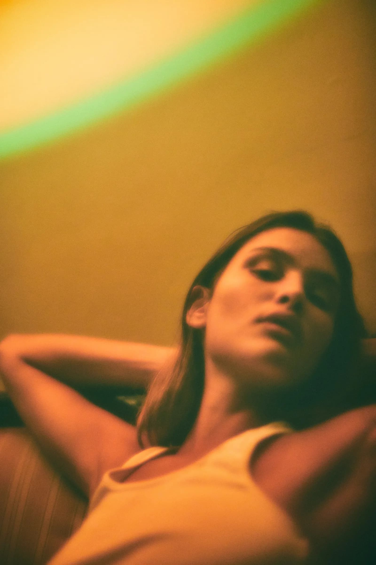 Retrato de mujer recostada bajo una luz de arcoíris
