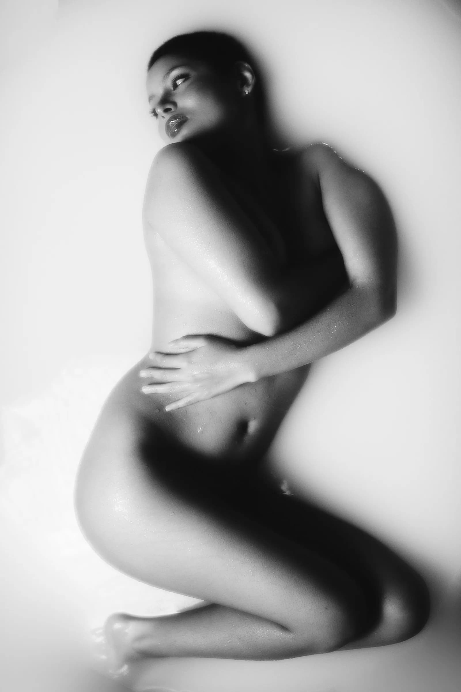 Retrato en blanco y negro de mujer recostada en un baño de leche