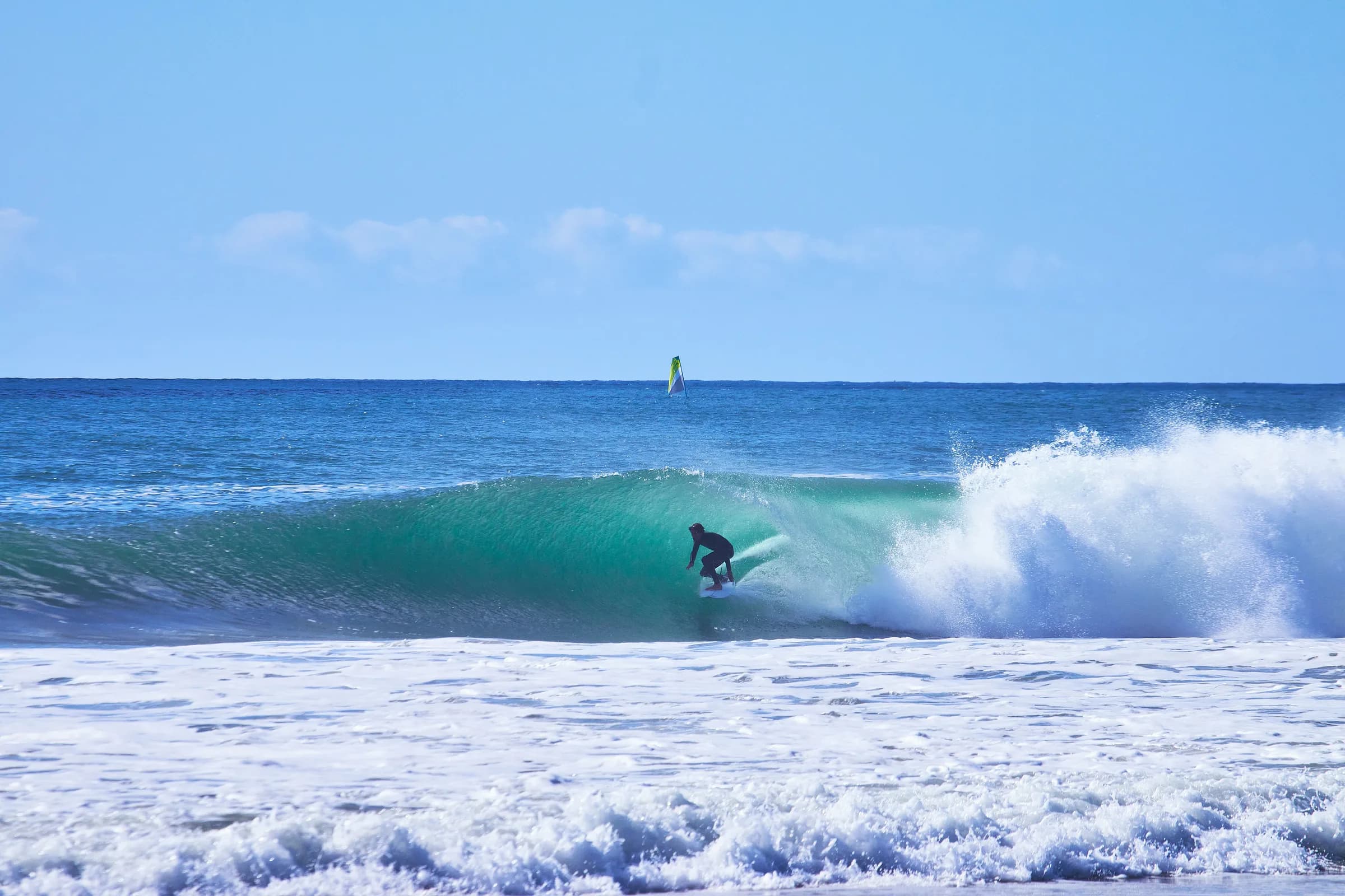 Surfista dentro de una ola turquesa en un día soleado