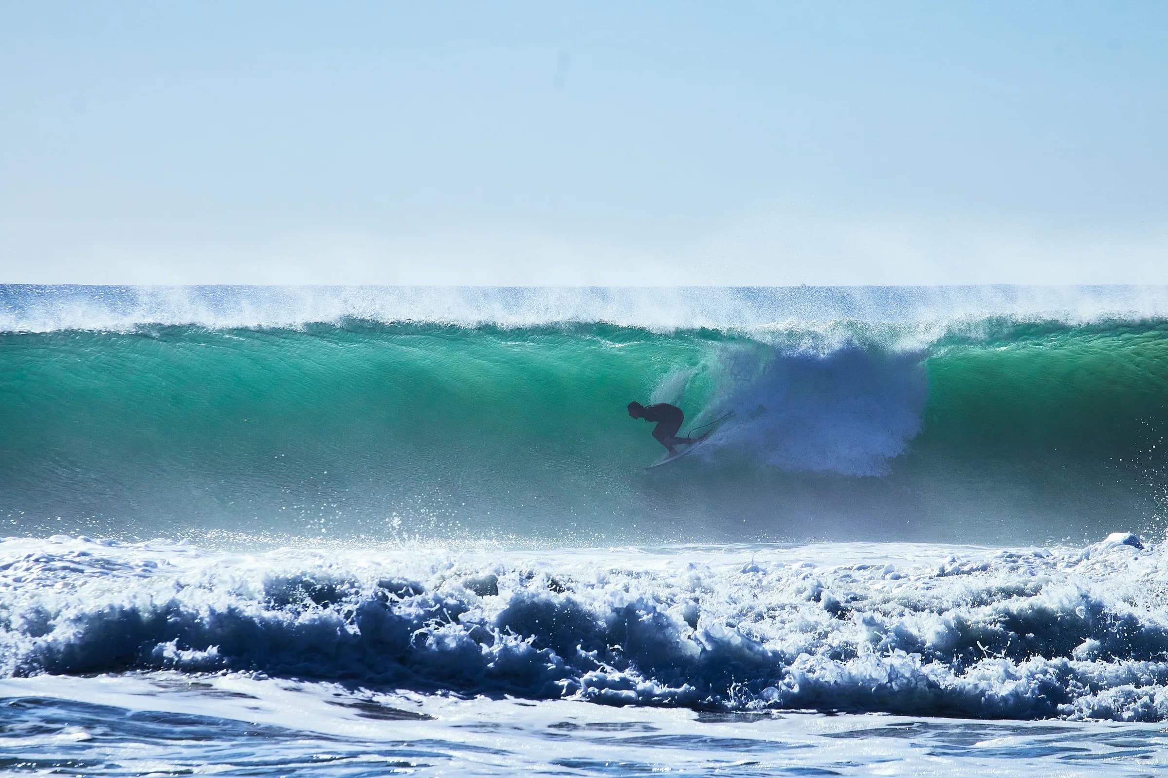 Surfista entrando al tubo de una ola verde levantada por el viento