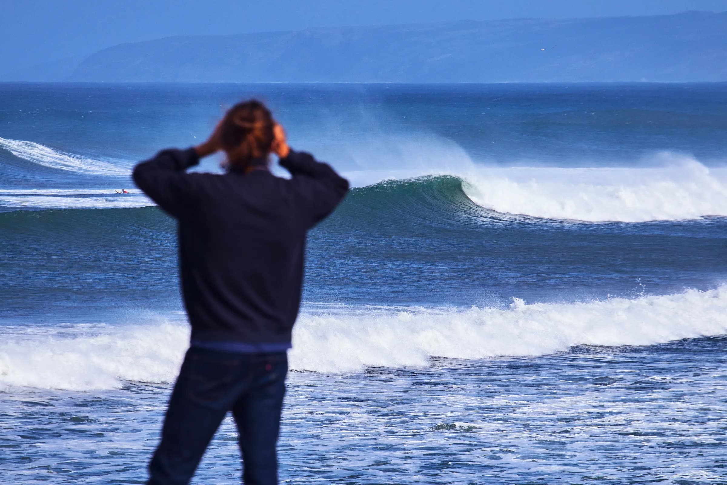 Espectador mirando romper una ola grande frente a la costa