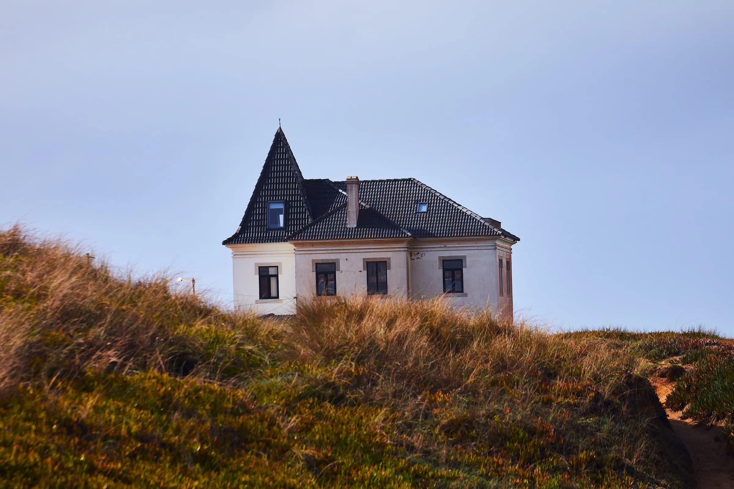 Casa antigua con torre sobre una duna de pasto