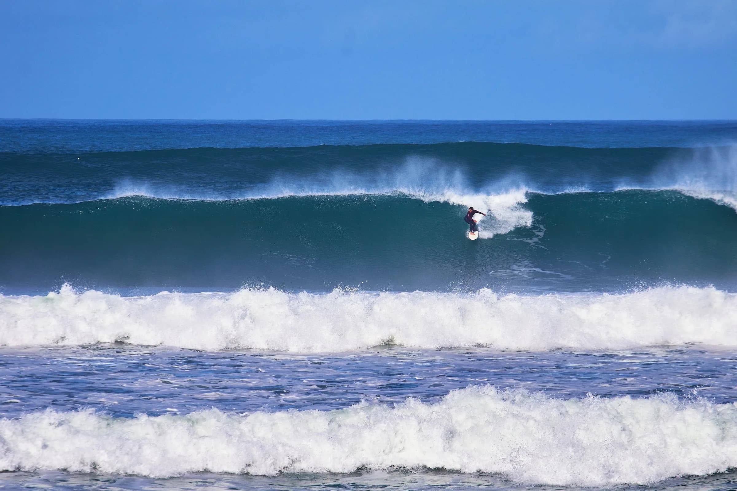 Surfista girando en la cresta de una ola azul