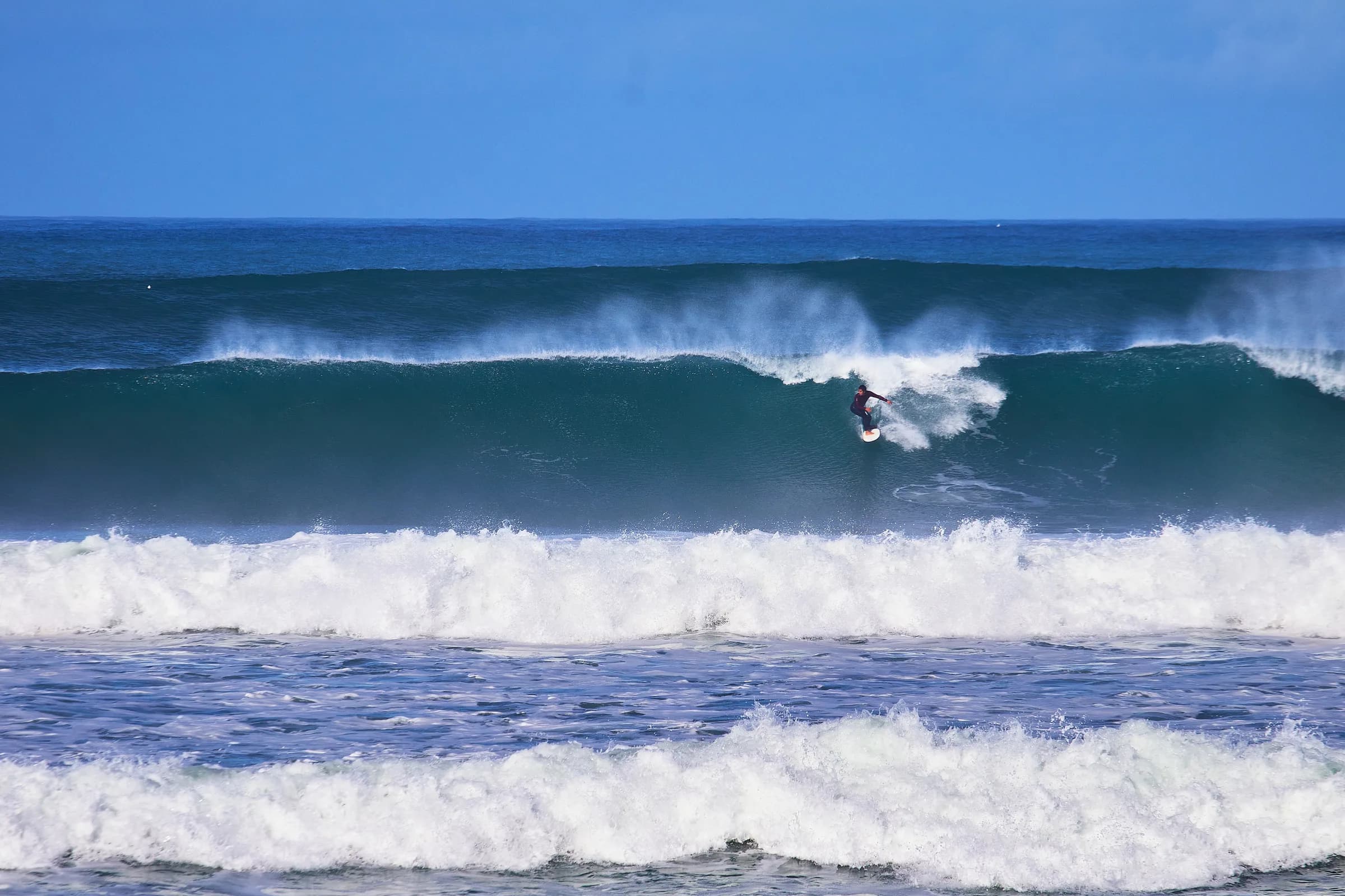 Surfista maniobrando en una ola grande de mar abierto