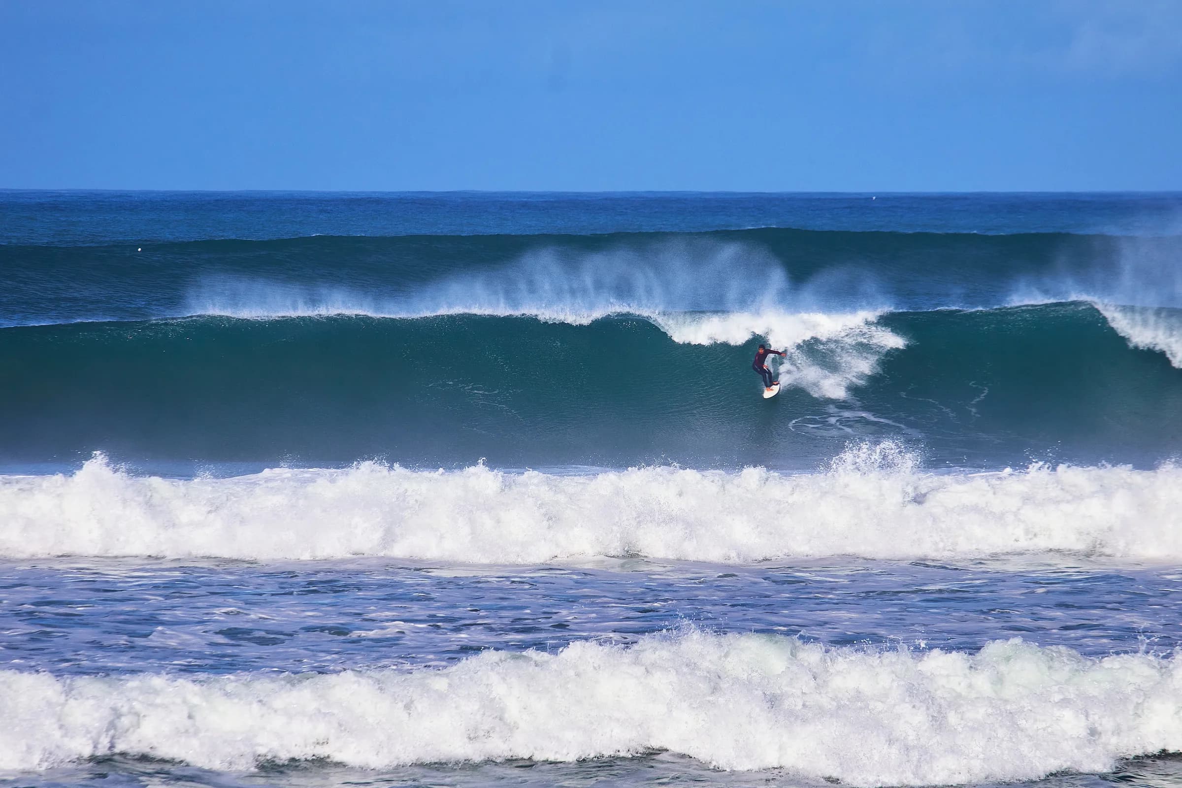 Surfista en la pared de una ola grande con rocío al viento