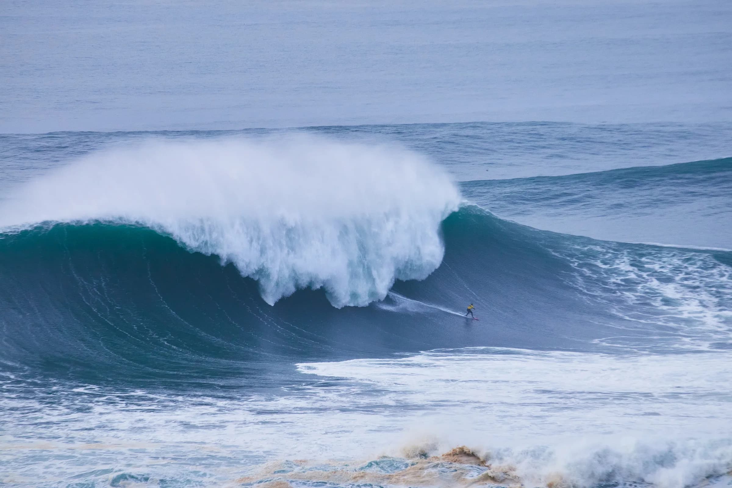 Surfista bajando una ola gigante en Nazaré